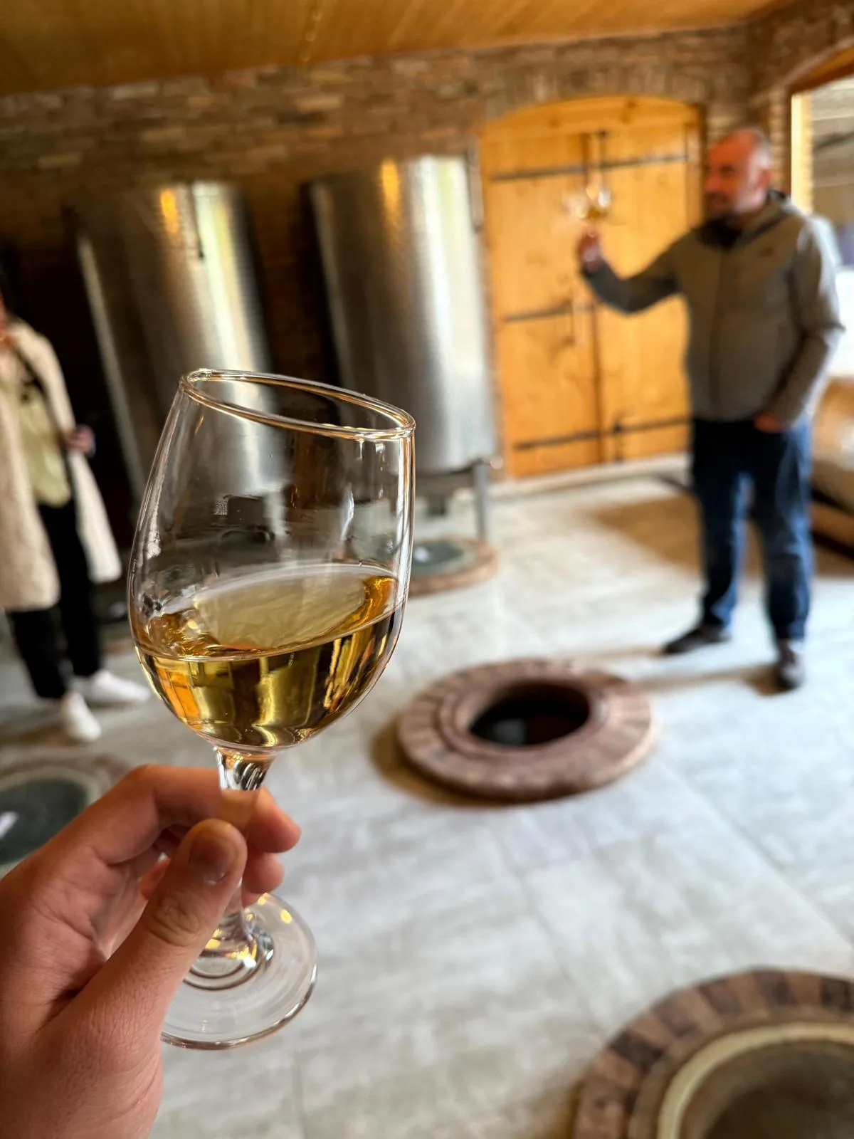 Ein Glas bernsteinfarbener Wein wird in einem Weinkeller in die Höhe gehalten